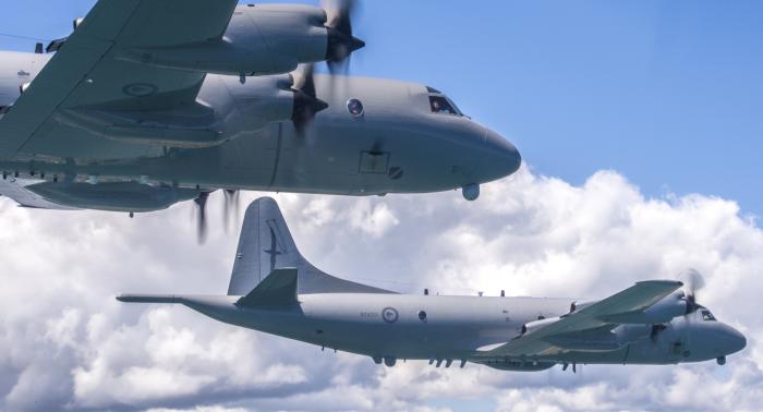 Two of the three grey Orion aircraft in a 'V' formation over Suburbia during their farewell flypast