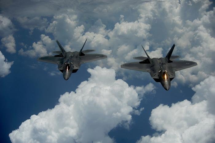 A pair of USAF F-22A Raptors pull away after being refuelled by a KC-135 Stratotanker over the Ocean