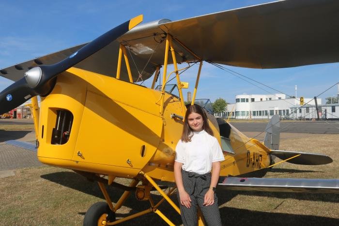 Selma Gage, recipient of the 2022 Sir Geoffrey de Havilland Flying Scholarship, with Cambridge Flying Group Tiger Moth G-AHIZ.