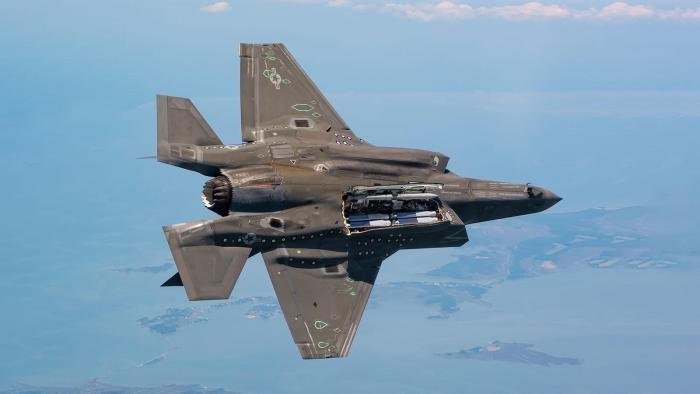 An F-35B Lightning II peels away with its internal weapons bay doors open, showing what appears to be four GBU-53/B StormBreaker air-launched, precision-guided glide bombs inside.