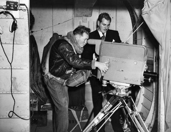 Still firmly on the ground, BBC cameraman Duncan Anderson wields the Marconi Mk1a Image Orthicon camera in the door of the Bristol Freighter during preparations for Operation ‘Pegasus’. With him stands assistant television outside broadcast manager Peter Dimmock.