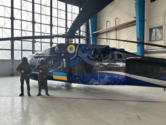 Armed crew members pose for a photo next to what is believed to be Sikorsky UH-60A Black Hawk (registration N60FW, ex-US Army serial 80-12355) - which was formerly operated by US-based Ace Aeronautics - in a hangar at an undisclosed location in Ukraine on February 21, 2023.